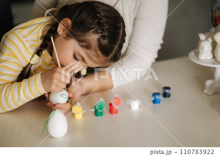 Portrait of mom and daughter painting easter eggs on kitchen. Spring holidays mood. Family 110783922