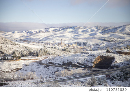 Snow. Winter landscape covered in a white blanket of snow covering mountains and roads. Trees with snow. Clear day. White blanket due to a storm with heavy snowfall. In Spain. January. 2024. 110785029