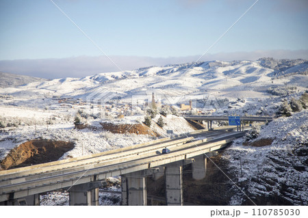 Snow. Winter landscape covered in a white blanket of snow covering mountains and roads. Trees with snow. Clear day. White blanket due to a storm with heavy snowfall. In Spain. January. 2024. Snow. Winter landscape covered in a white blanket of snow covering mountains and roads. Trees with snow. Clear day. White blanket due to a storm with heavy snowfall. In Spain. January. 2024. 110785030