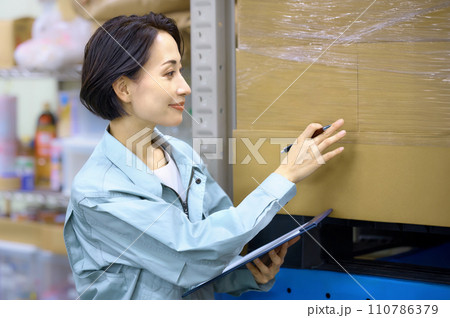 倉庫で棚卸しする作業着の女性作業員 倉庫で棚卸しする作業着の女性作業員 110786379