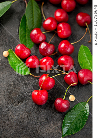 Ripe sweet cherry berry with leaves on a black wooden board. 110786648
