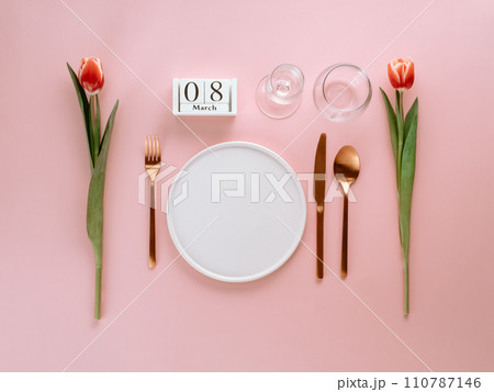 8 march table setting. Empty white plate, calendar with march eight date and red tulip on pink background. Aesthetic stylish dinner table setting for Women's day. Copy space. Flat lay 110787146