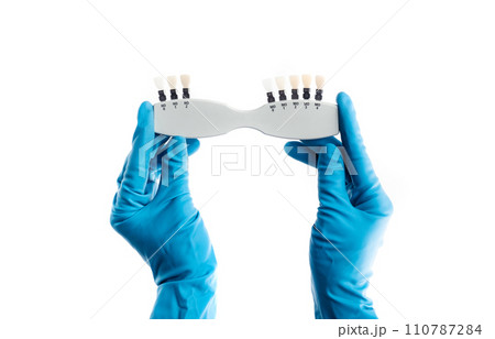 Hands in blue gloves holding dental color palette isolated 110787284