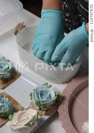 A woman sprinkles homemade zephyr with powdered sugar. Flowers from zephyr. An entrepreneur at work. Homemade zephyr. 110787670