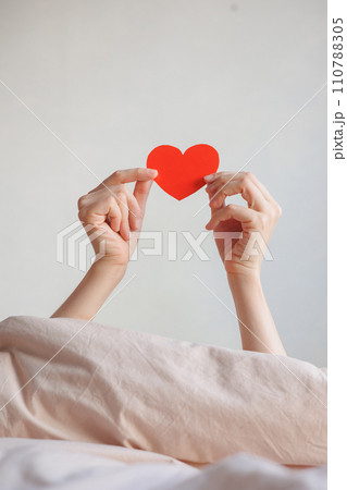 women's hands holding red heart shaped postcard, surprise gift for Valentine's day. women's hands holding red heart shaped postcard, surprise gift for Valentine's day. 110788305