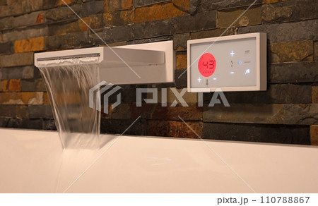 Modern digital watertap, filling the white bath 110788867