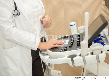 Close-up of Gynecologist doctor hand with high-tech ultrasound machine with backlight. Close-up of Gynecologist doctor hand with high-tech ultrasound machine with backlight. 110789963