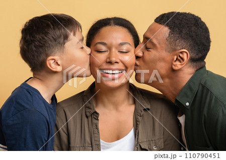 Loving black father and son kissing happy young woman Loving black father and son kissing happy young woman 110790451
