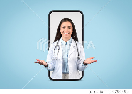 Friendly european female doctor with stethoscope emerges from smartphone screen, engaging with welcoming gesture 110790499
