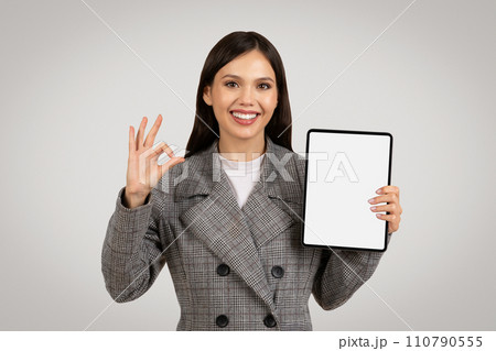 Happy woman holding tablet with blank screen showing okay sign 110790555