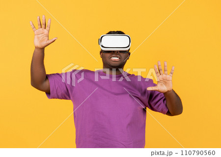 black man engrossed in simulation game via VR headset, studio 110790560
