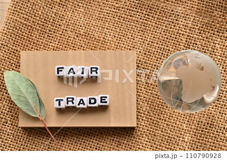 FAIR TRADEの語にワードビーズが並んでいる脇にガラスボールの地球がある 110790928