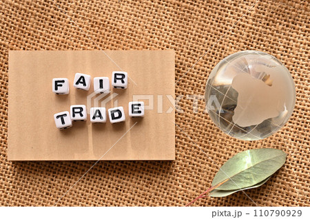 FAIR TRADEの語にワードビーズが並んでいる脇にガラスボールの地球がある 110790929