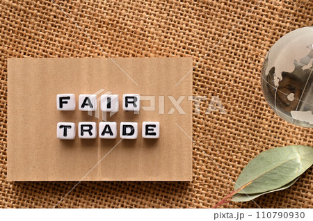 FAIR TRADEの語にワードビーズが並んでいる脇にガラスボールの地球がある 110790930