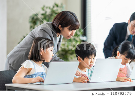 プログラミング学習をしている小学生と先生。 110792579