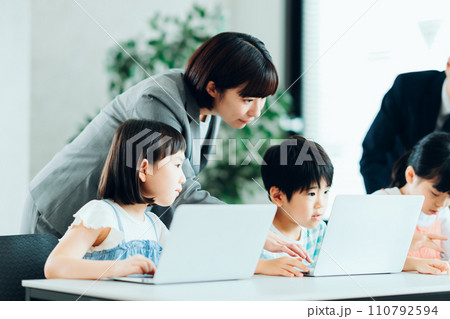 プログラミング学習をしている小学生と先生。 110792594