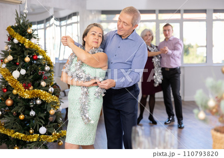 Happy mature woman enjoying impassioned merengue with male partner in dance room during celebration Christmas and New Year. Social dancing concept Happy mature woman enjoying impassioned merengue with male partner in dance room during celebration Christmas and New Year. Social dancing concept 110793820