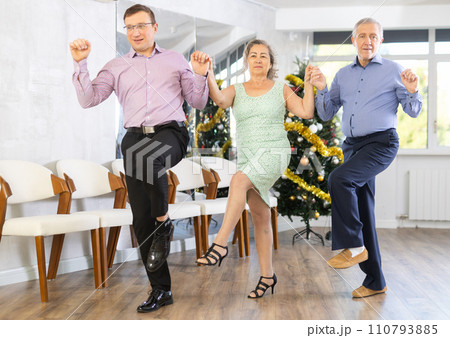 Mature people dancing Greek typical sirtaki dance at dance hall during celebration Christmas and New Year Mature people dancing Greek typical sirtaki dance at dance hall during celebration Christmas and New Year 110793885