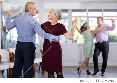Group of active aged people rehearsing social dance in pair in dance hall 110794295