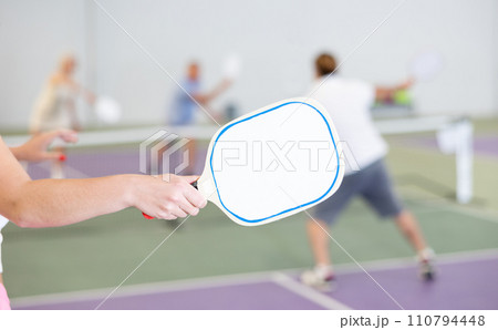 Paddle-shaped racquet for pickleball in hand of female player 110794448
