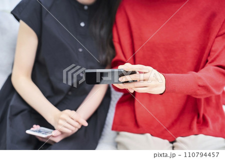 スマートフォンの画面を見ている女性達の手元 110794457