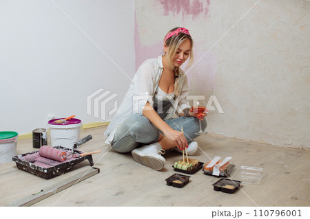 Sexy girl designer eats sushi on the construction site. painter has lunch after work.Concept interior design and room repair Sexy girl designer eats sushi on the construction site. painter has lunch after work.Concept interior design and room repair 110796001