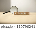 Fund and bond investment. Bond investment planning and economic data analysis. Small wooden blocks and magnifying glasses. 110796241
