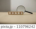 Fund and bond investment. Bond investment planning and economic data analysis. Small wooden blocks and magnifying glasses. 110796242