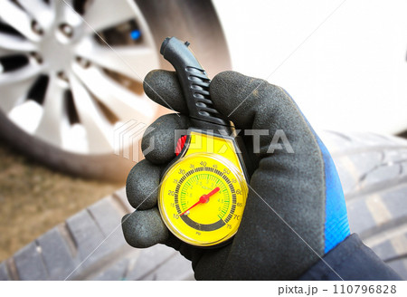 Car mechanic or driver checks tire pressure with a car tire pressure gauge 110796828