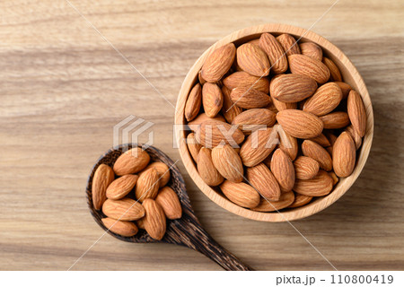 Raw almond in bowl with spoon on wooden background, Table top view Raw almond in bowl with spoon on wooden background, Table top view 110800419