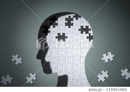 認知症やアルツハイマー病など、記憶を失うイメージ。人の頭のシルエットとピースが欠けたジグソーパズル。 110801060