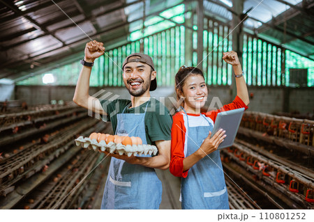 worker couple raise both hands carrying egg tray and pad 110801252