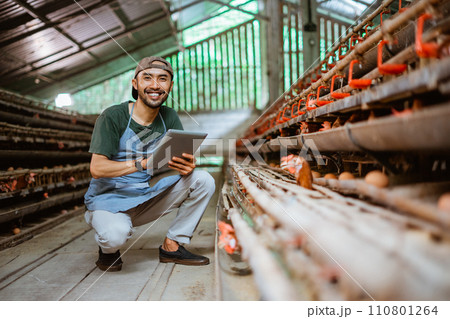 Smiling businessman holding a pad close to a chicken coop Smiling businessman holding a pad close to a chicken coop 110801264