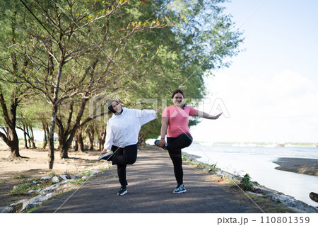 asian women in sportswear stretching together outside 110801359
