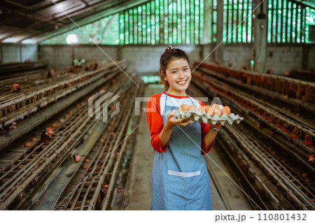 Smiling Asian female entrepreneur carrying a tray of eggs Smiling Asian female entrepreneur carrying a tray of eggs 110801432