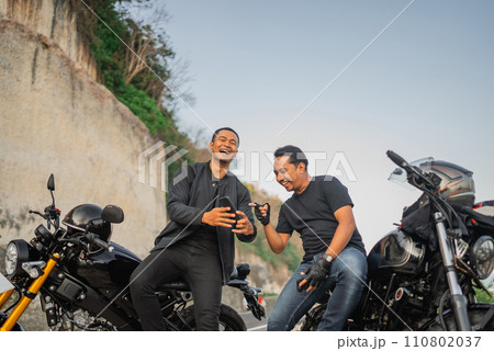 happy indonesian riders watching phone together 110802037