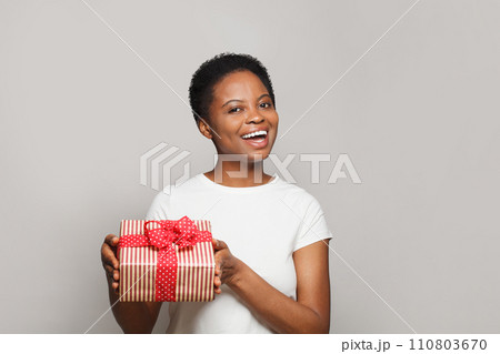 Excited happy young woman with gift present box standing on white background 110803670