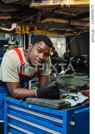 Portrait of young african man car service worker wearing uniform standing in garage 110804675