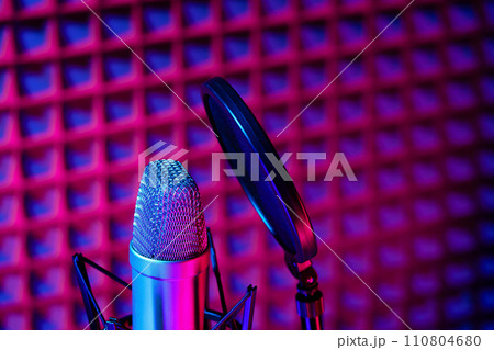 Professional studio microphone against acoustic foam panel background in neon light 110804680