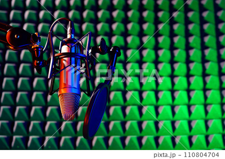 Professional studio microphone against acoustic foam panel background in neon light 110804704