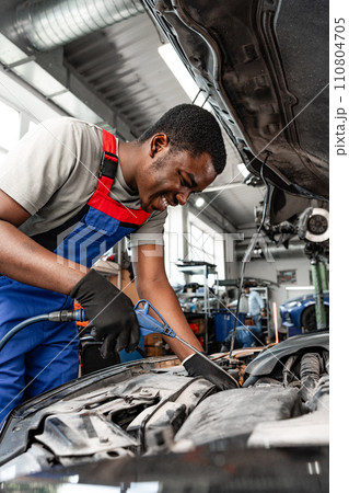 Young African male mechanic repairs car in garage close up 110804705