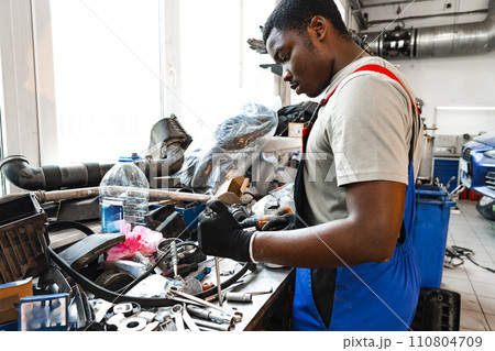 Young african mechanic in uniform working in a car service shop 110804709