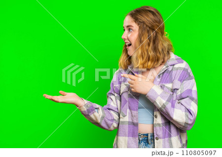 Young woman showing thumbs up and pointing at left on blank space place for your advertisement logo 110805097