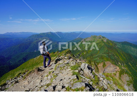 ニぺソツ山頂上から石狩岳への稜線を眺める登山者 110806618