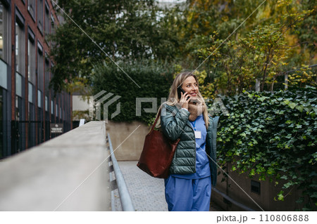 Female nurse, doctor going home from work, phone calling on smartphone. Work-life balance of healthcare worker as parent and partner. Female nurse, doctor going home from work, phone calling on smartphone. Work-life balance of healthcare worker as parent and partner. 110806888