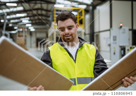 Portrait of young man with Down syndrome working in warehouse. Concept of workers with disabilities, support in workplace. 110806945