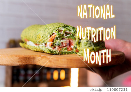 Celebrating National Nutrition Month With a Healthy Spinach Wrap on Wooden Board 110807231