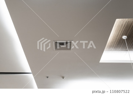 Ceiling mounted cassette type air conditioner and modern lamp light on white ceiling. Duct air conditioner for home, hall or office. 110807522