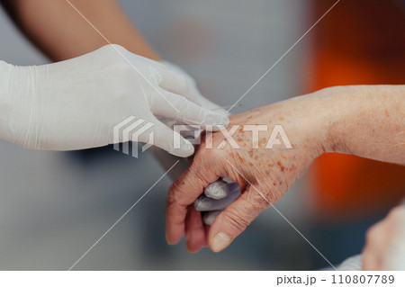 Close up of nurse insering IV cannula in vein, hand. Senior woman in intensive care unit in hospital. IV, intravenous therapy for elderly patient. 110807789