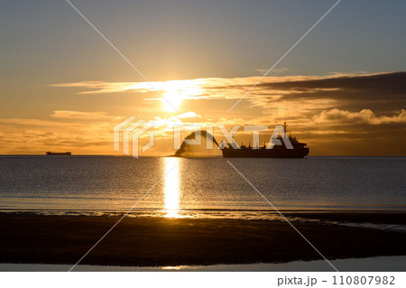 Vessel engaged in dredging at sunset time. Hopper dredger working at sea. Ship excavating material from a water environment. Beautiful sunset. 110807982